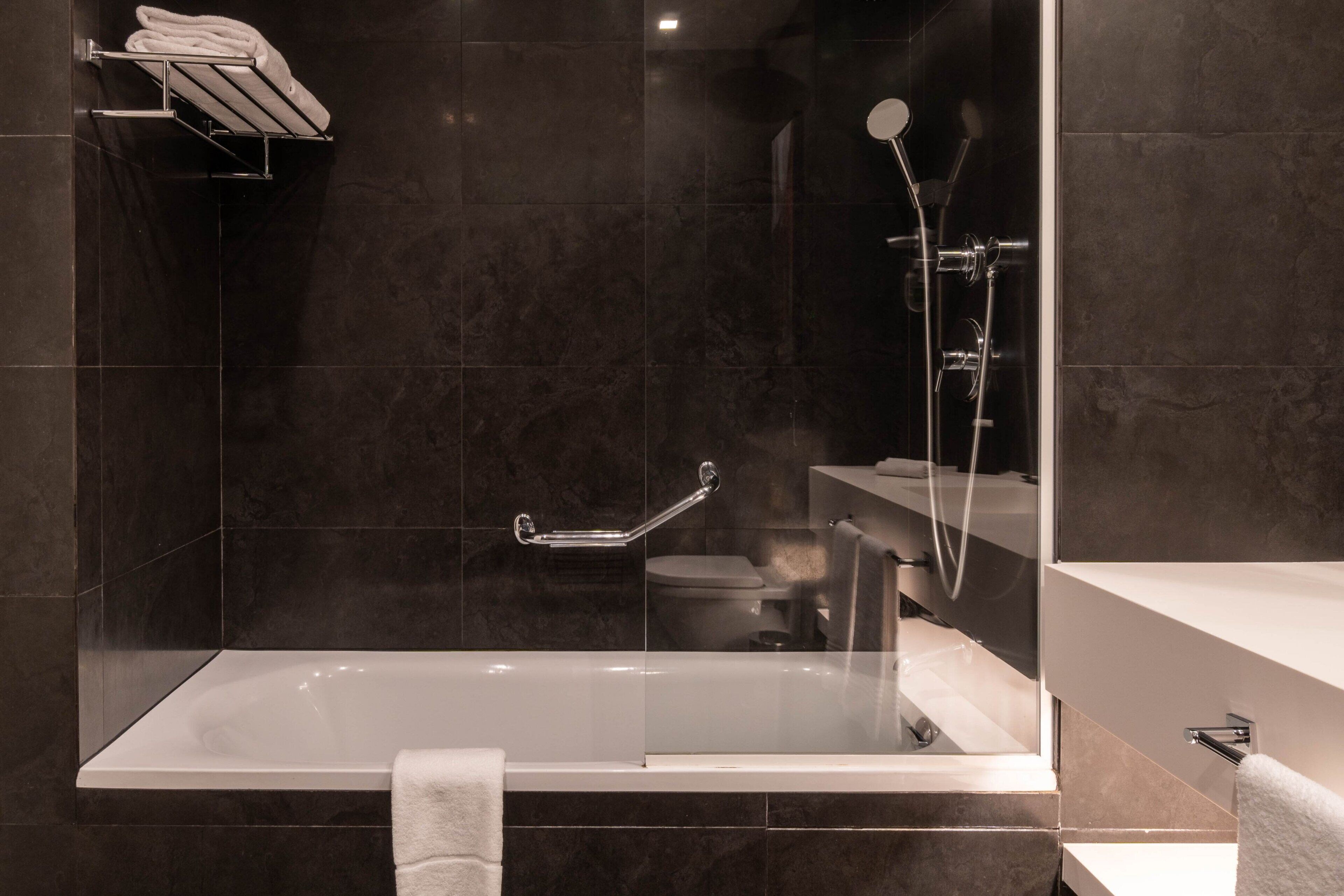 Un baño moderno con ducha de vidrio, una bañera blanca y un tocador con espejo.