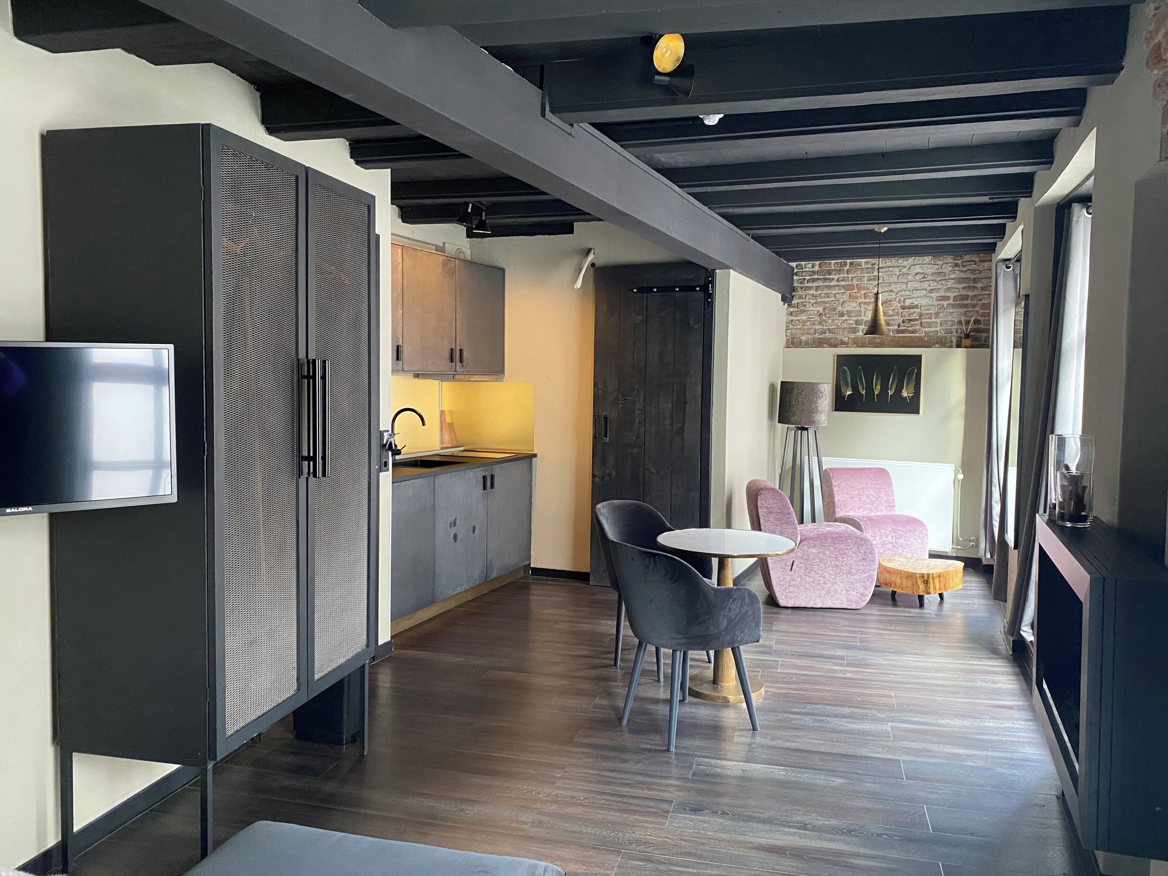 A modern kitchen with a built-in TV, wooden cabinets, and a dining area with a round table and chairs.