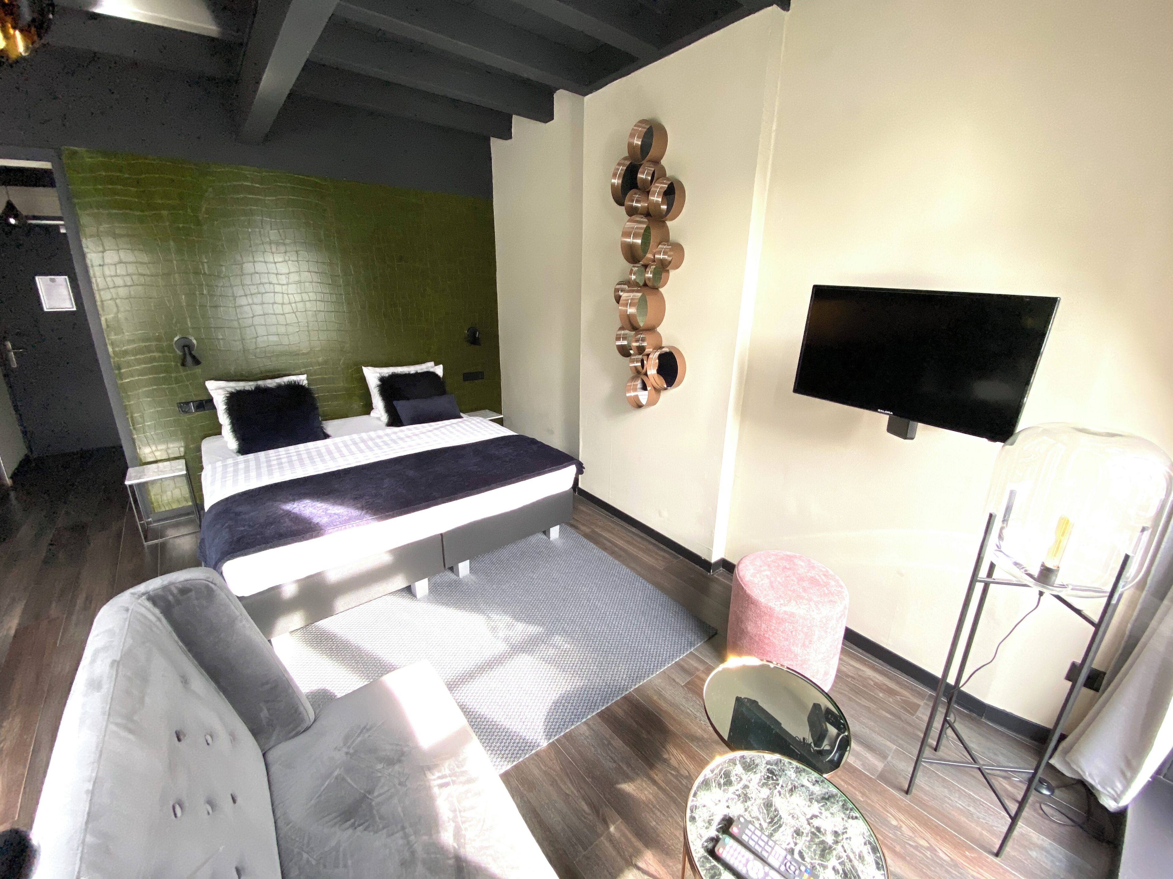 Una habitación de hotel moderna con una cama, un sofá, un televisor y una mesita.