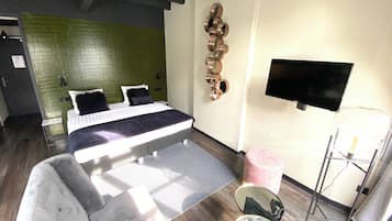 Una habitación de hotel moderna con una cama, un sofá, un televisor y una mesita.