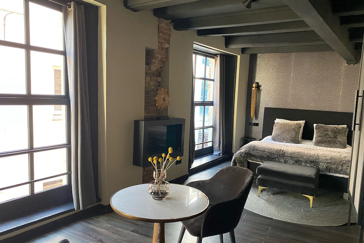 Une chambre d’hôtel avec un lit, une télévision, une table avec des chaises et de grandes fenêtres.
