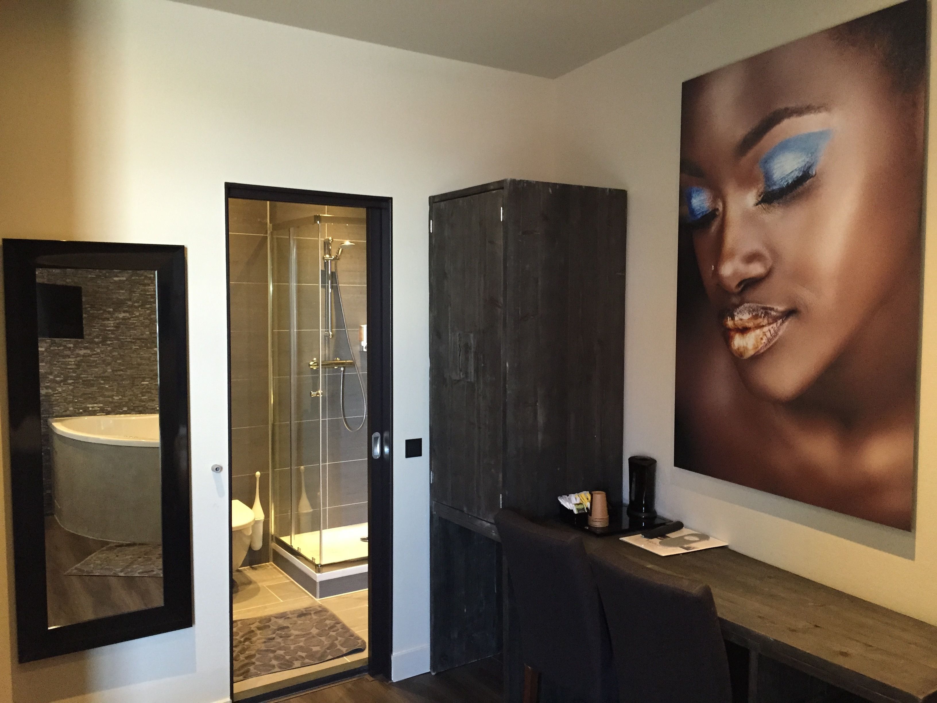 Un baño moderno con cabina de ducha de vidrio, un mueble oscuro y una obra de arte grande enmarcada en la pared.