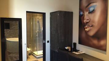 Un baño moderno con cabina de ducha de vidrio, un mueble oscuro y una obra de arte grande enmarcada en la pared.