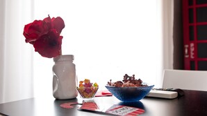 A table with a vase of red flowers, a bowl of colorful candies, and a bowl of chocolate pieces. - Il Giglio Rosso - B&B (Florence)