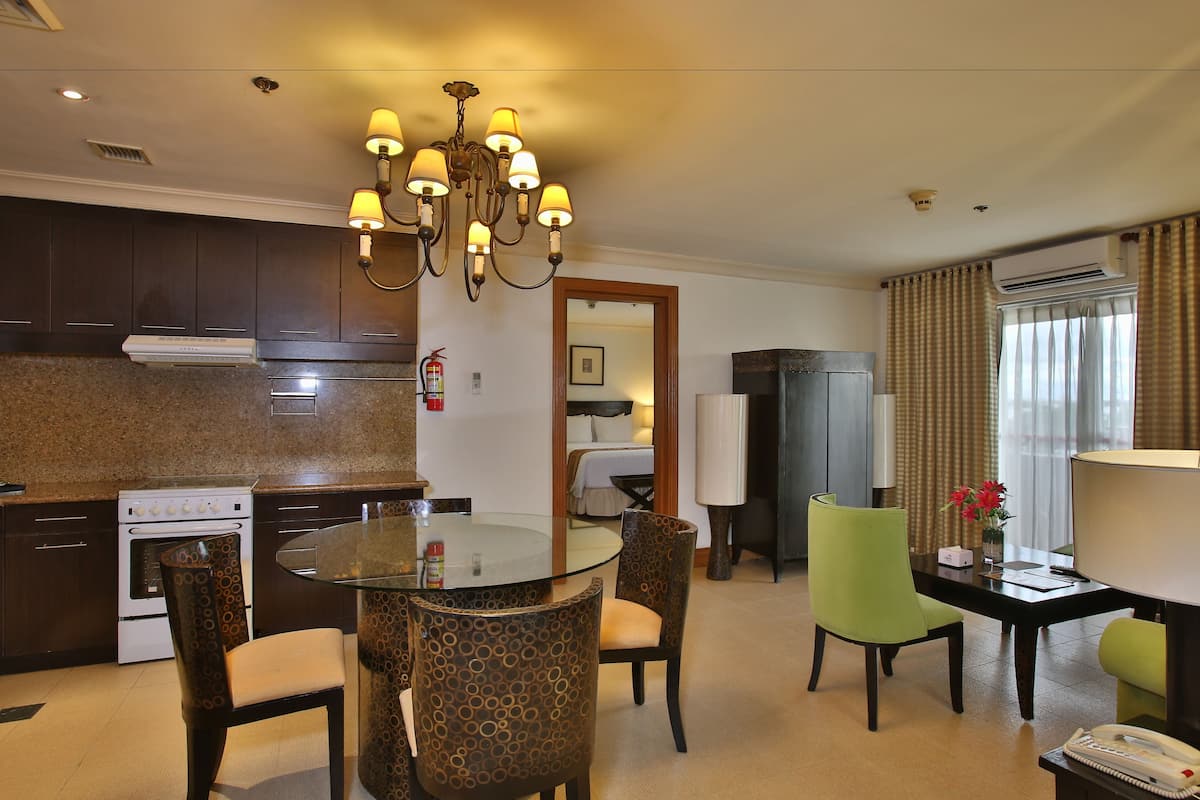 A hotel room with a kitchen, dining area, and a living space.