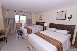 A hotel room with two beds, a chair, a small table, and a balcony with curtains. - Crown Regency Suites & Residences - Mactan (Lapu-Lapu)