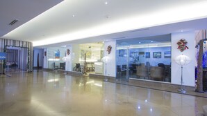 A modern hotel lobby with a cafe, seating area, and glass doors leading to a dining space. - Crown Regency Suites & Residences - Mactan (Lapu-Lapu)