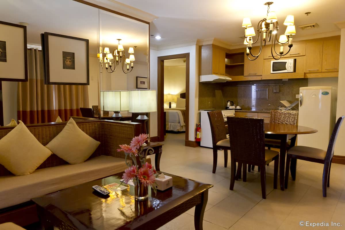 A hotel room with a living area, dining table, and kitchenette.