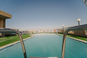 Una piscina al aire libre, una piscina en la azotea, sombrillas