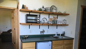 A compact kitchen with wooden cabinets, a built-in oven, a refrigerator, and a countertop with a sink.