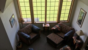 A living room with a large window, two sofas, a small table, and a lamp.