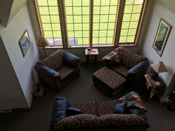 A living room with a large window, two sofas, a small table, and a lamp. - Second Wind Country Inn (Ashland)