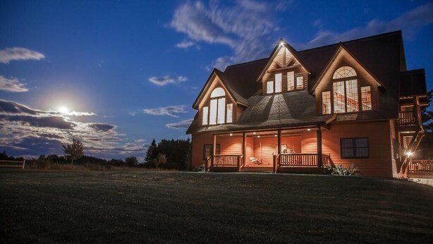 A large, two-story house with a wrap-around porch and a staircase leading to the upper level.