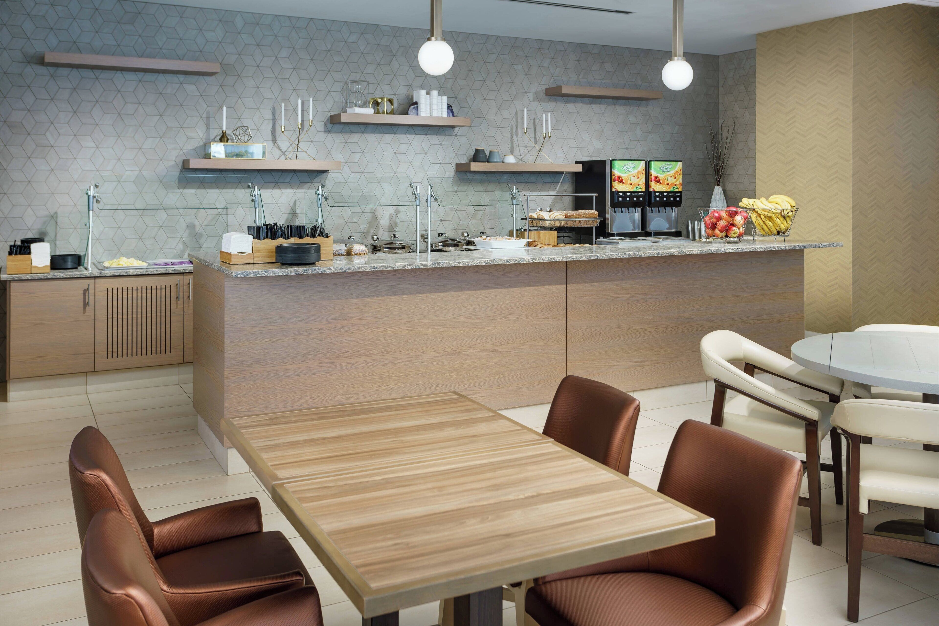 A modern kitchen with a central island, built-in appliances, and a dining area with leather chairs.