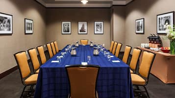 A conference room with a long table, chairs, and framed pictures on the walls.