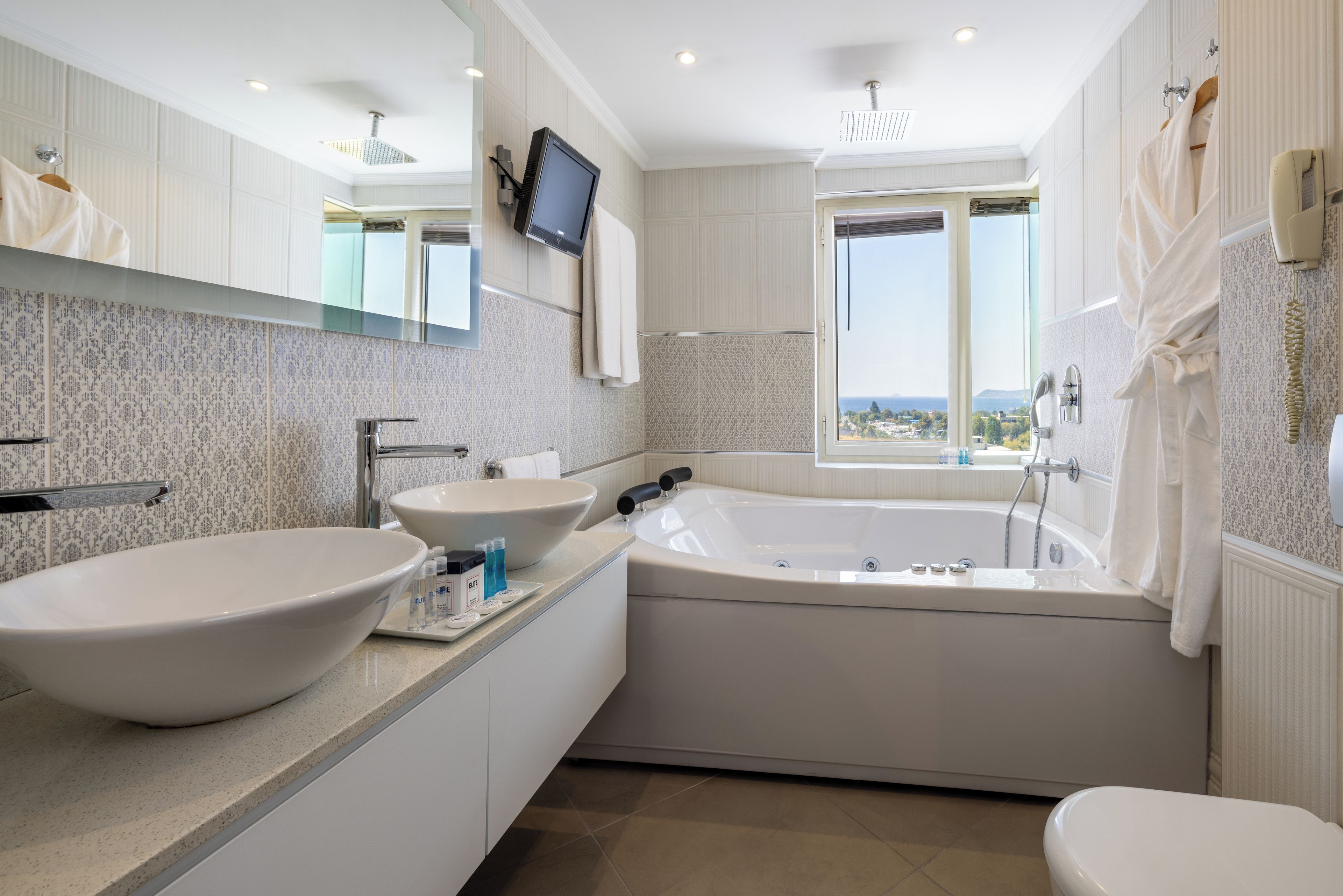 Un baño moderno con dos lavamanos grandes, una bañera y un ventanal con vistas.