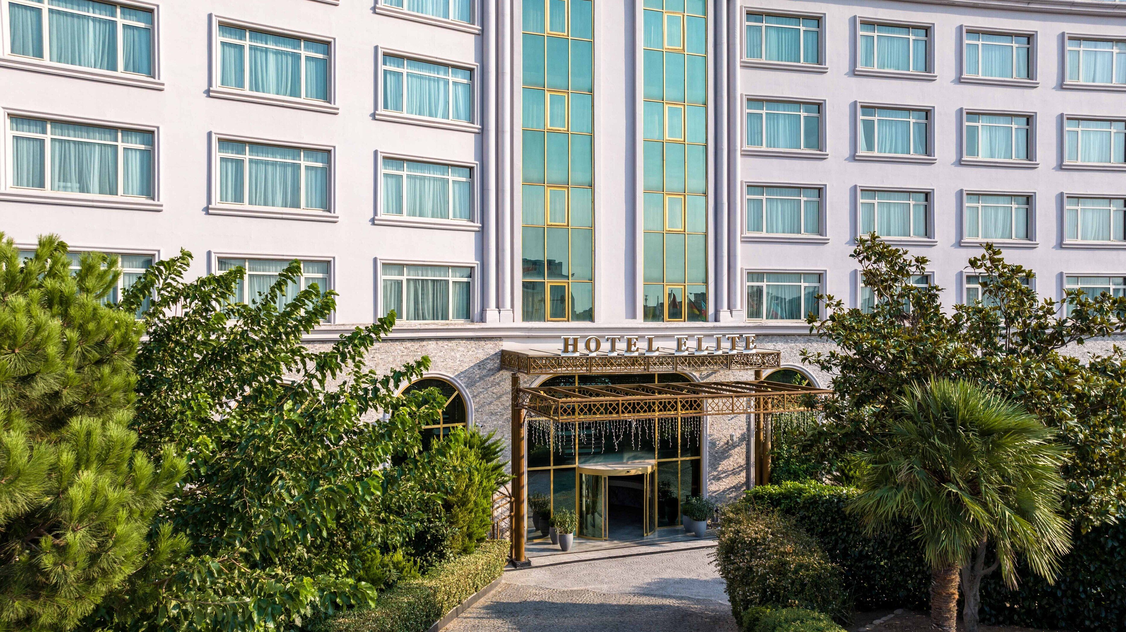 A multi-story hotel with a prominent entrance, large windows, and a well-maintained garden.