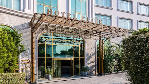 L’entrée d’un hôtel, avec un auvent en fer forgé et des portes en verre.