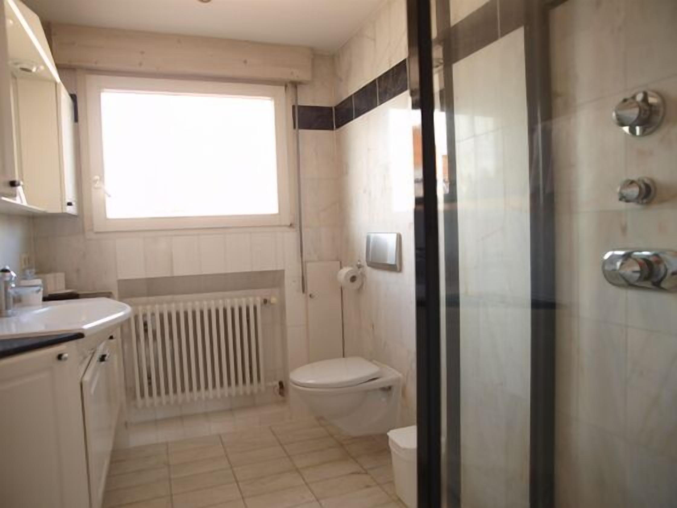 Un baño con inodoro, ducha y ventana.