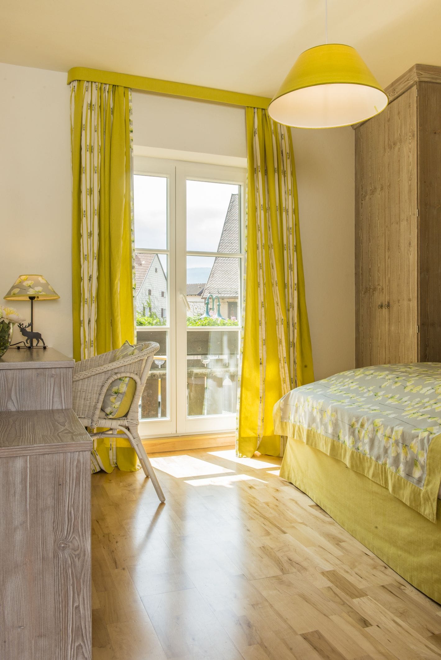A room with a bed, a chair, a desk, and a window with curtains.