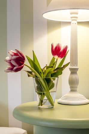 A clear glass vase with water and flowers on a table, next to a white lamp. - Hotel Sonne (Kirchzarten)