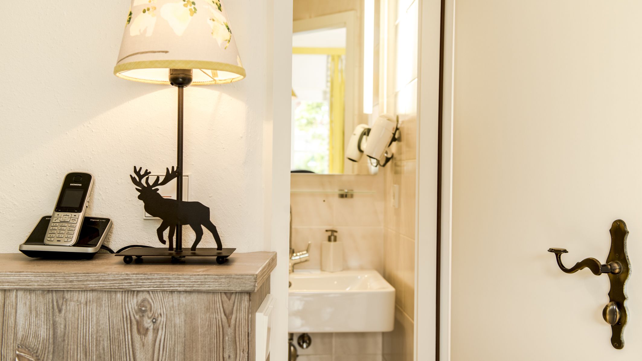 A bathroom with a sink, mirror, and a decorative deer sculpture on a wooden surface.
