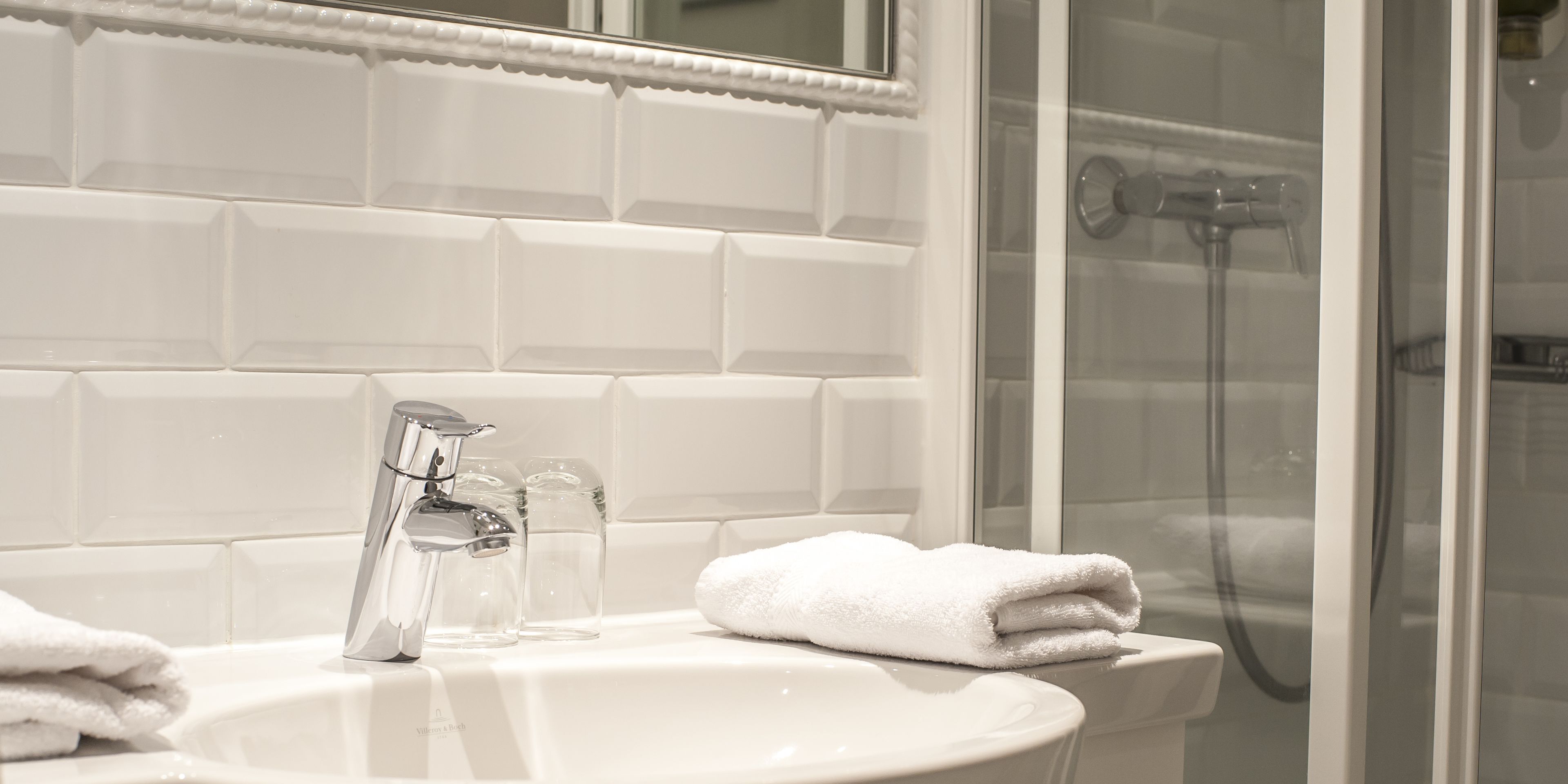 A bathroom with a white sink, a mirror, and a glass-enclosed shower.