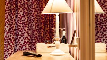 A wooden table with a remote control, a lamp, and a bottle of wine.