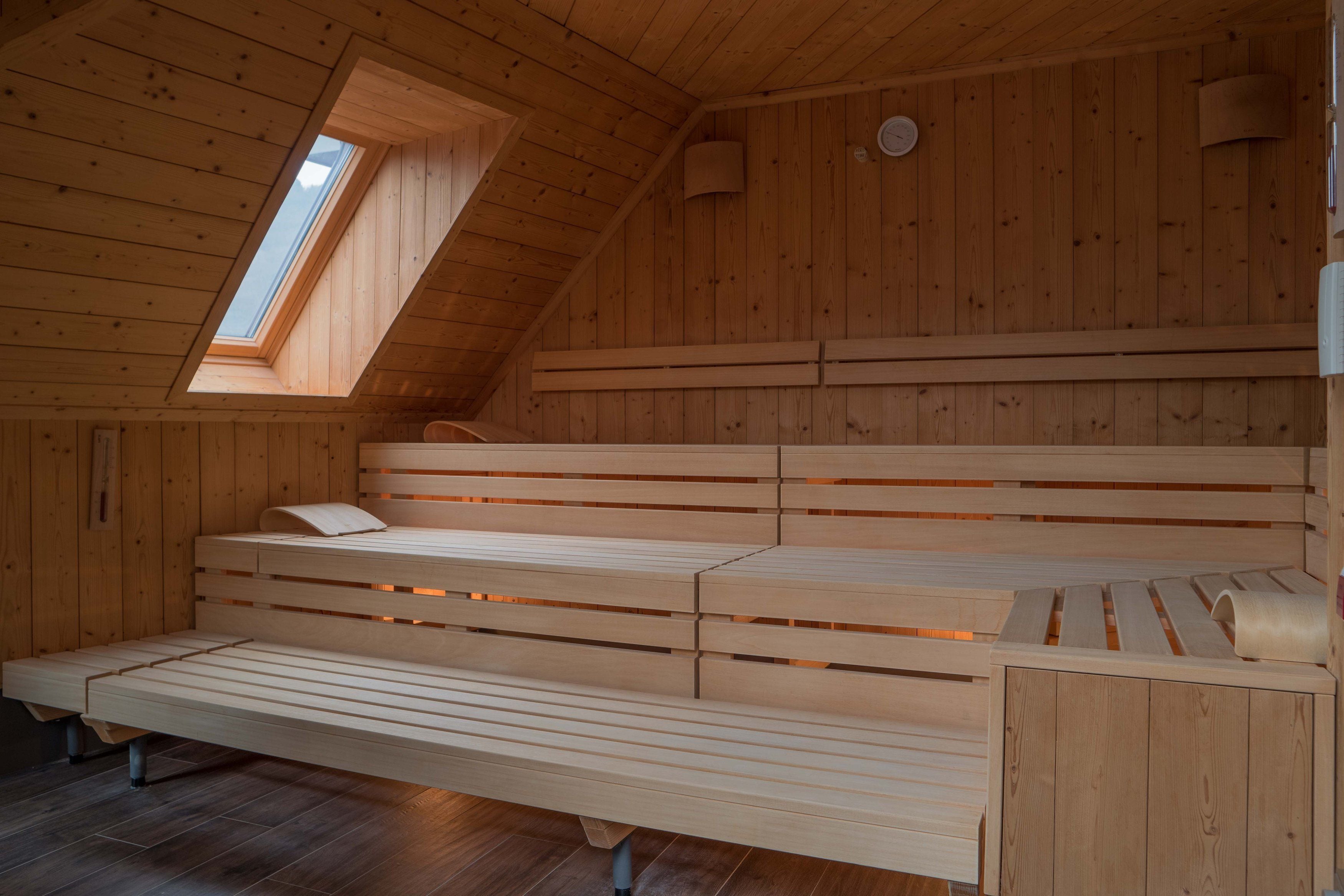 A wooden interior with a sloped ceiling, a skylight, and a bench with a pillow.