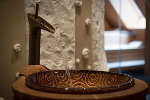 Una fuente decorativa con un caño de metal y un recipiente estampado.