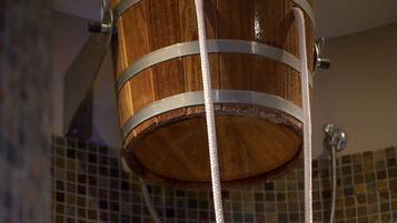 A wooden bucket shower with metal straps and a hose.