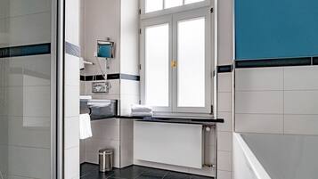 A modern bathroom with a window, a towel rack, and a radiator.