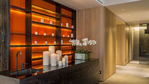 Une salle de bain moderne avec un meuble-lavabo en bois foncé, des étagères éclairées par des bougies et une orchidée en pot.
