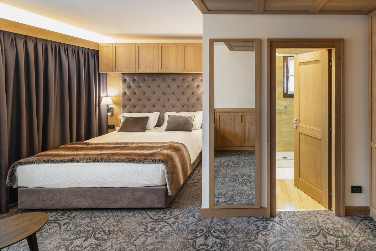 Un dormitorio con una cama grande, cabecera de madera, mesita de noche y un espejo.