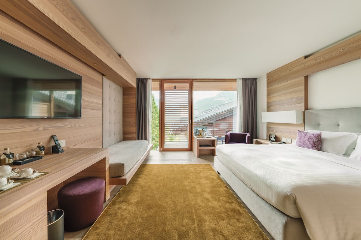 Una habitación de hotel moderna con una pared de madera, una cama grande, un escritorio con una silla y un televisor.