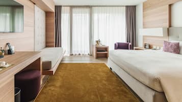 Une chambre d’hôtel moderne équipée d’un lit, d’un bureau, d’une chaise, d’une télévision et d’une fenêtre avec des rideaux.