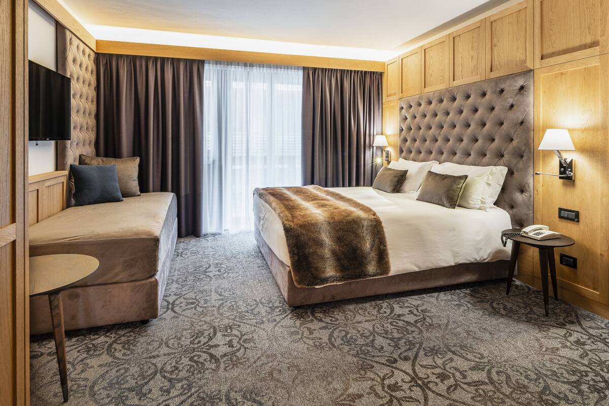Una habitación de hotel con una cama grande, un sofá, una mesita y un televisor.