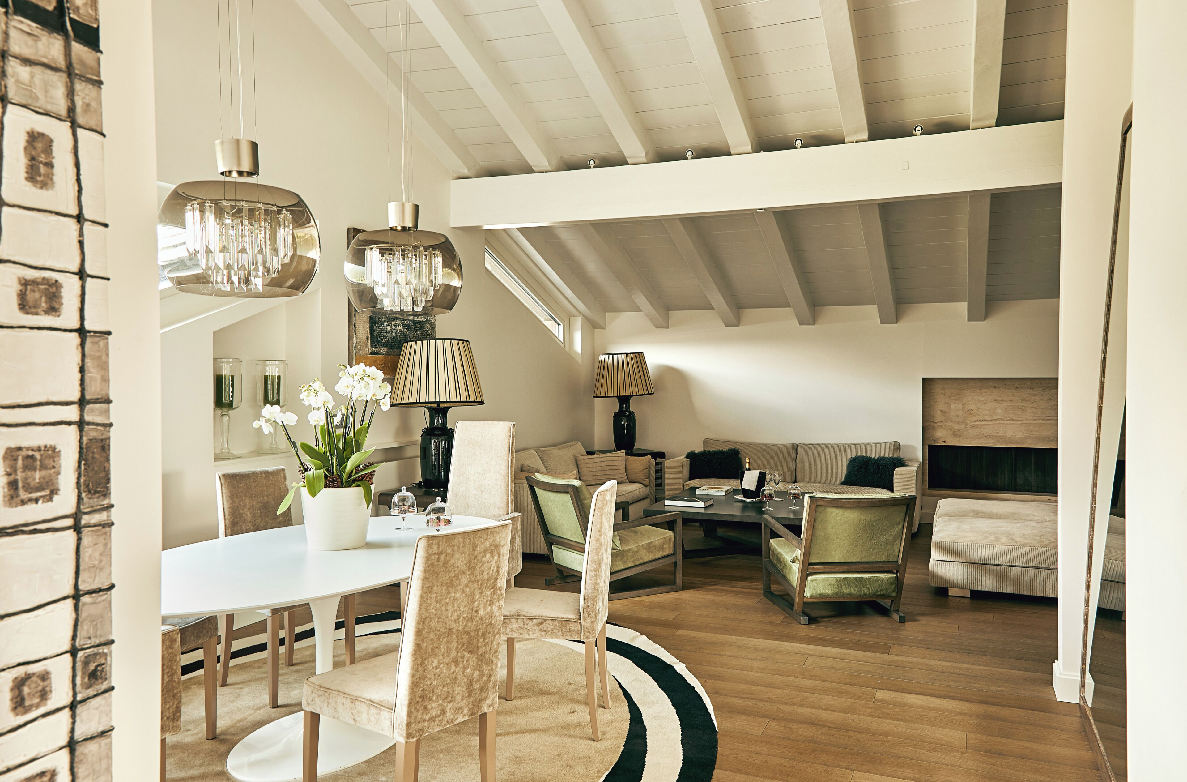 A spacious living area with a high ceiling, a dining table with chairs, and a seating area with sofas and a coffee table.