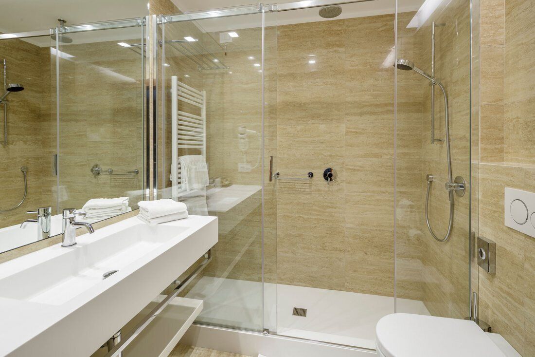 Un baño moderno con ducha envuelta en vidrio, un lavabo blanco y un inodoro.
