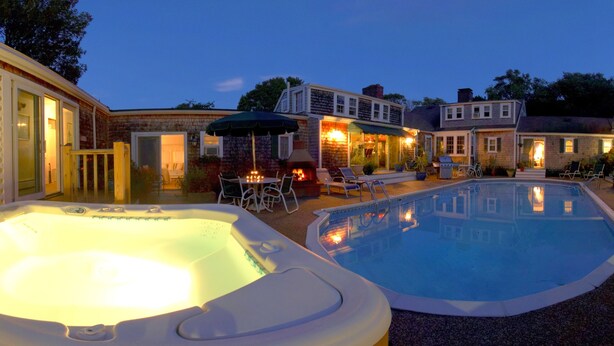 Ein Garten mit Whirlpool, Schwimmbad und einer Terrasse mit Stühlen und Tisch.