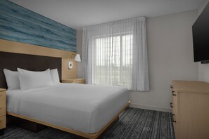 Een hotelkamer met een bed, nachtkastje, lamp en een kledingkast.