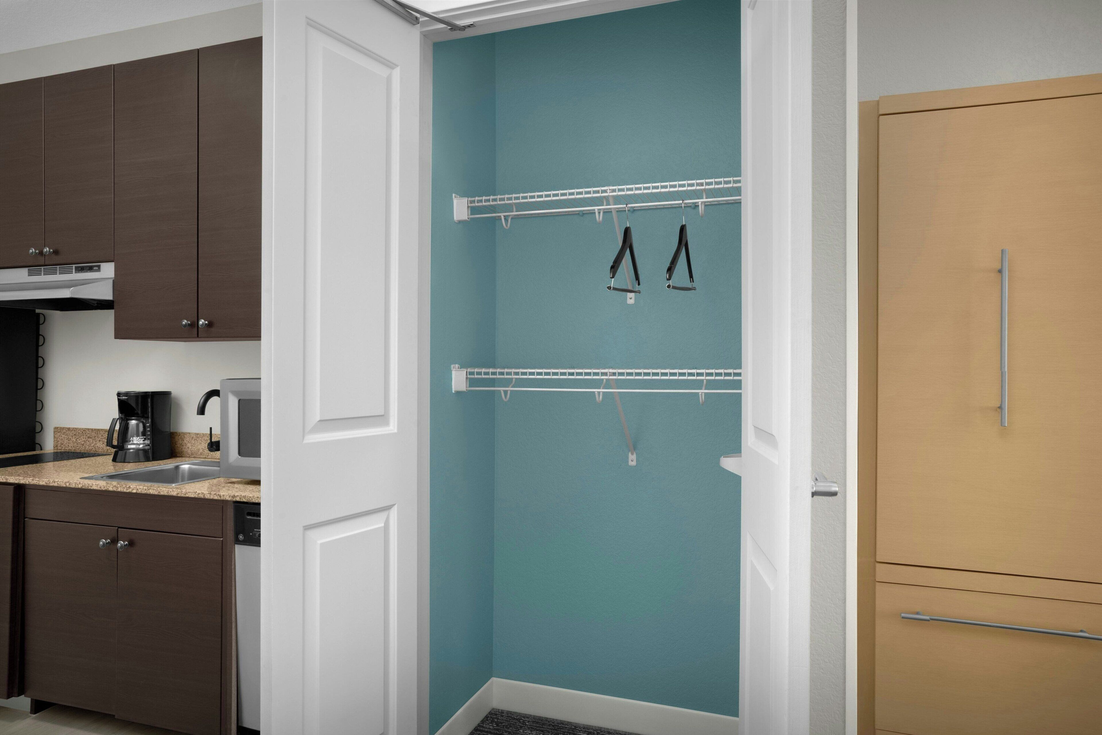 A modern kitchen with dark wooden cabinets, a white door, and a teal accent wall.