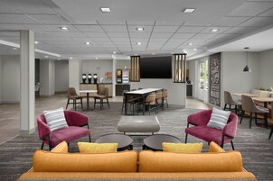 A modern lounge area with sofas, a coffee station, and a dining area.
