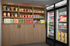 Een supermarkt met schappen vol snacks, drankjes en diepvriesproducten.