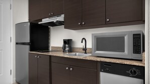 Une cuisine moderne avec des meubles de couleur brun foncé, un réfrigérateur en acier inoxydable, un four à micro-ondes encastré et un lave-vaisselle.