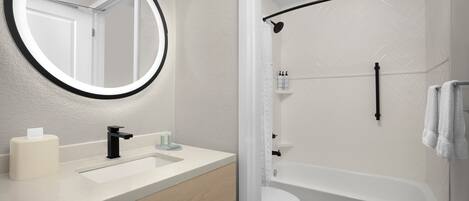 Un bagno con uno specchio rotondo, un lavandino, un water e una vasca da bagno.