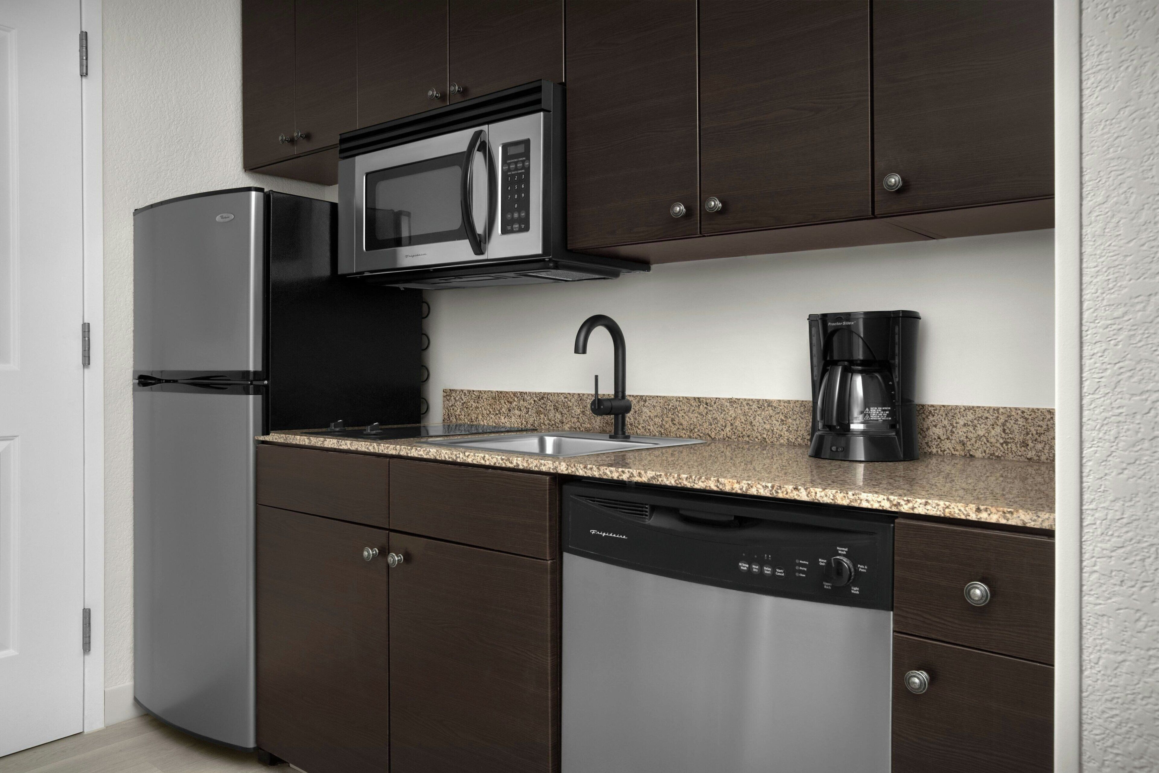 A modern kitchen with stainless steel appliances, a granite countertop, and dark cabinetry.