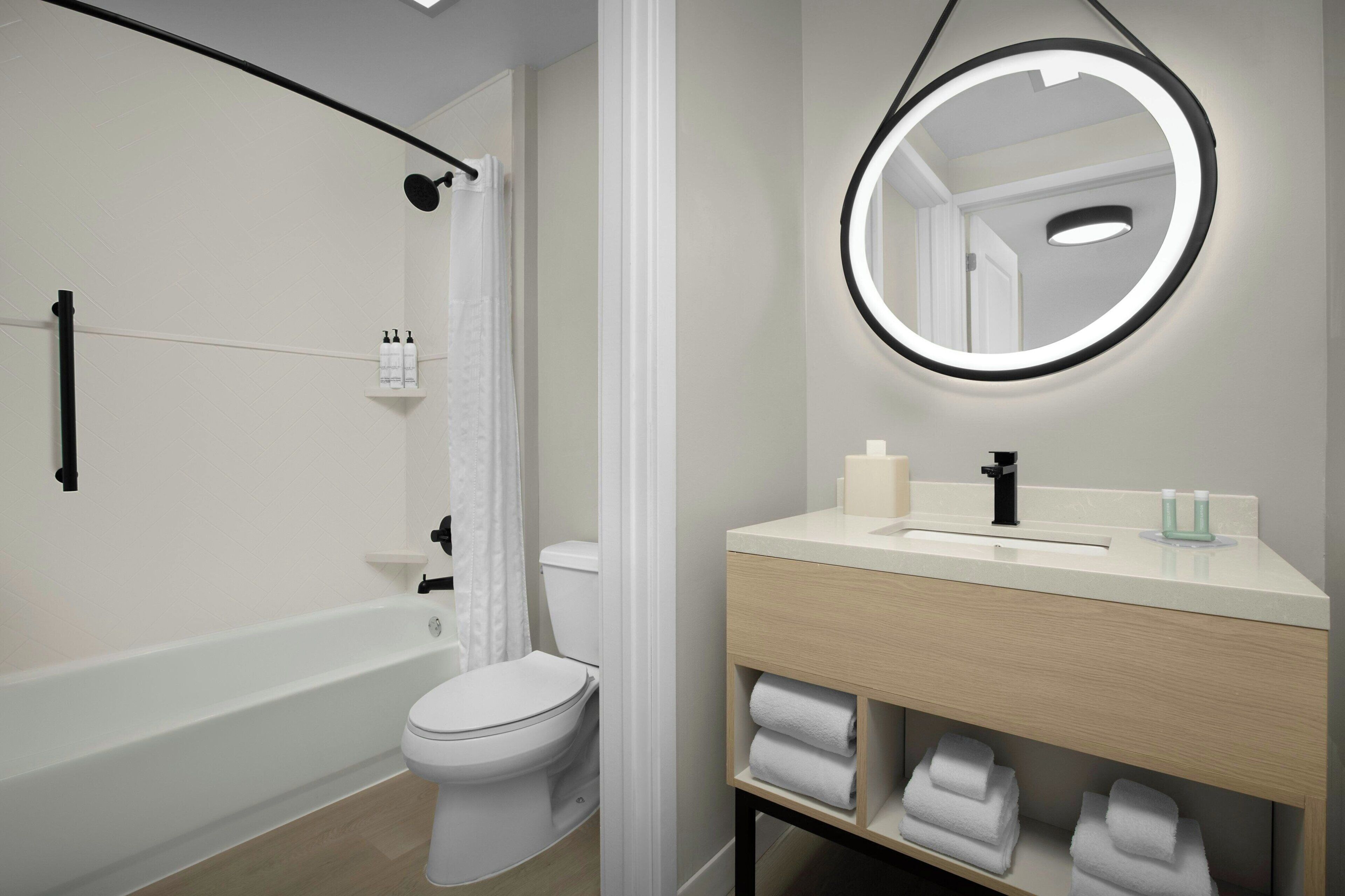 A modern bathroom with a bathtub, toilet, and vanity with a mirror.
