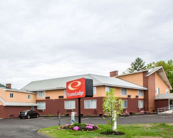 A hotel with a red sign reading "Econo Lodge." It features a modern design with a flat roof and brick accents. - Econo Lodge Lake Region (West Ossipee)