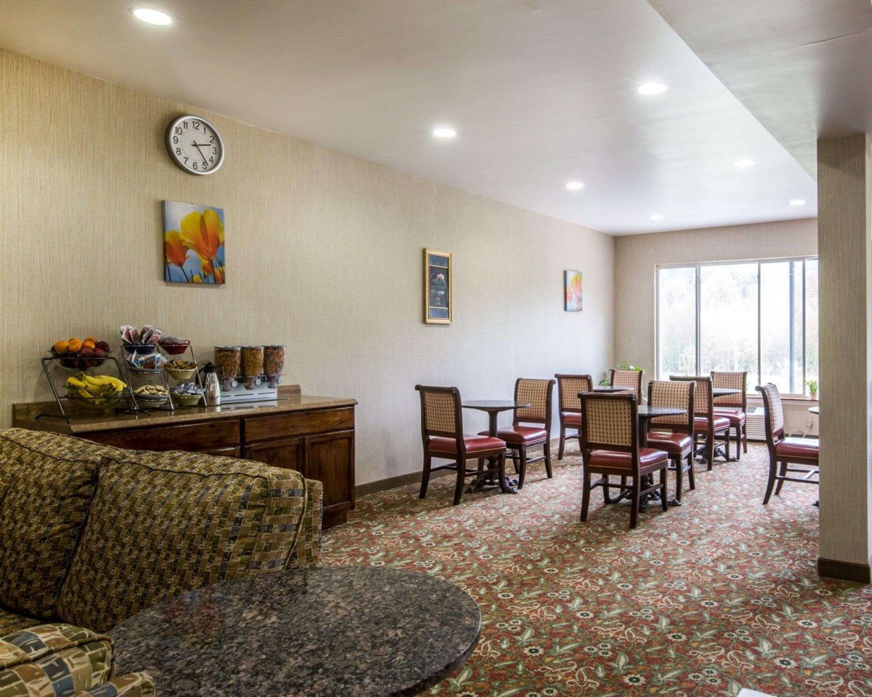 Uma área de jantar de hotel com buffet, relógio e quadros nas paredes.